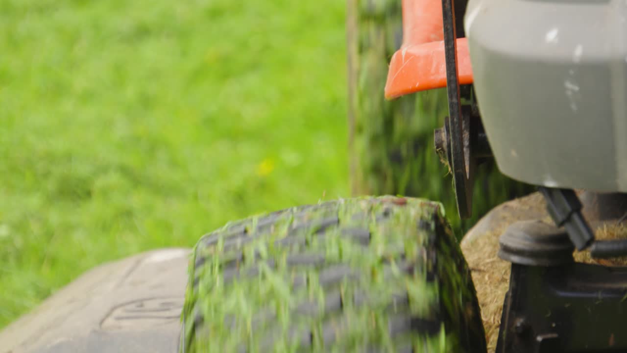 Ride-on Mower Moving Towards Camera with Grass Covered Tyres in Slow Motion. Perfect for gardening, landscaping, or satisfying nature visuals. 4K