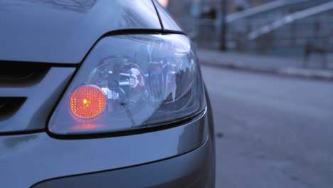 car is parked on the side of highway, turn signal flashes indicating drivers intention to make u-turn or go on road, close up. automobile turned on emergency light after accident, waiting for help