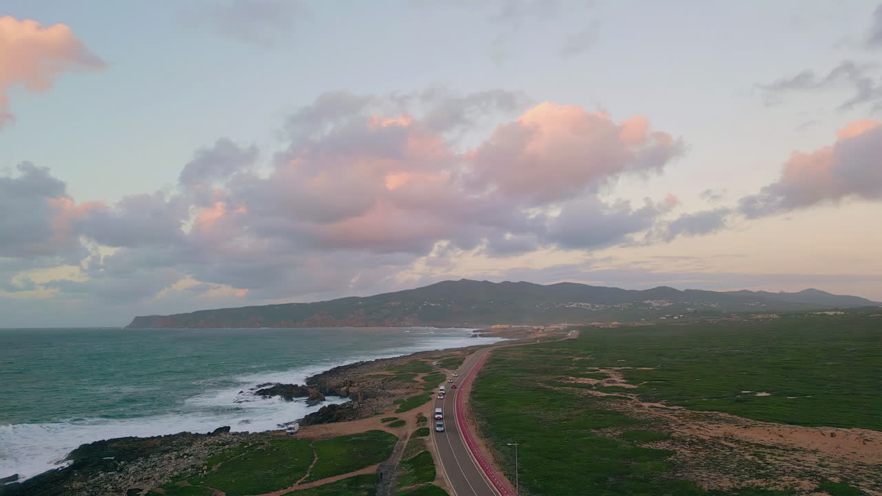 Road stretching rugged coastline under evening clouds drone view. Foamy ocean