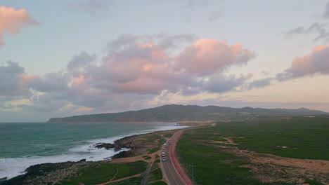 road stretching rugged coastline under evening clouds drone view. foamy ocean