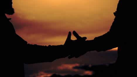 silhouetted hands against a warm sunset