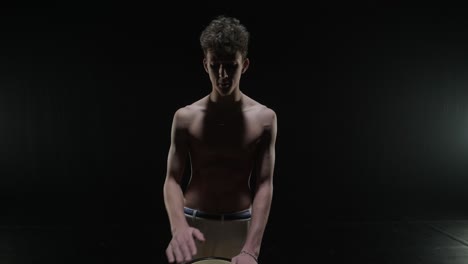 group of a professional dancers are practicing capoeira in darkness against a spotlight on a black background of studio. afro-brazilian martial art that combine elements of dance.