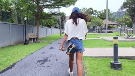 woman walking with a skateboard in a park