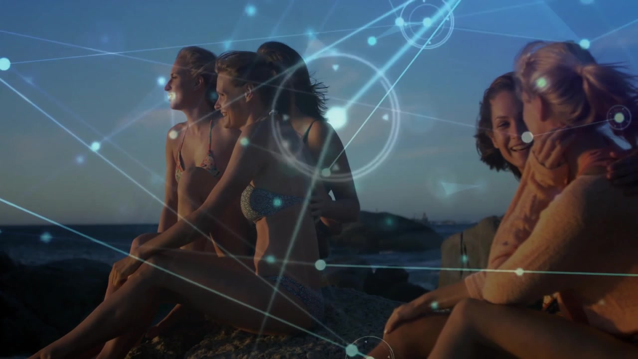 Drei Frauen, die sich bei Sonnenuntergang an einem Felsvorsprung niederlassen, leuchtende Knoten und Linien als Technologie-Overlay initiieren und lachen.