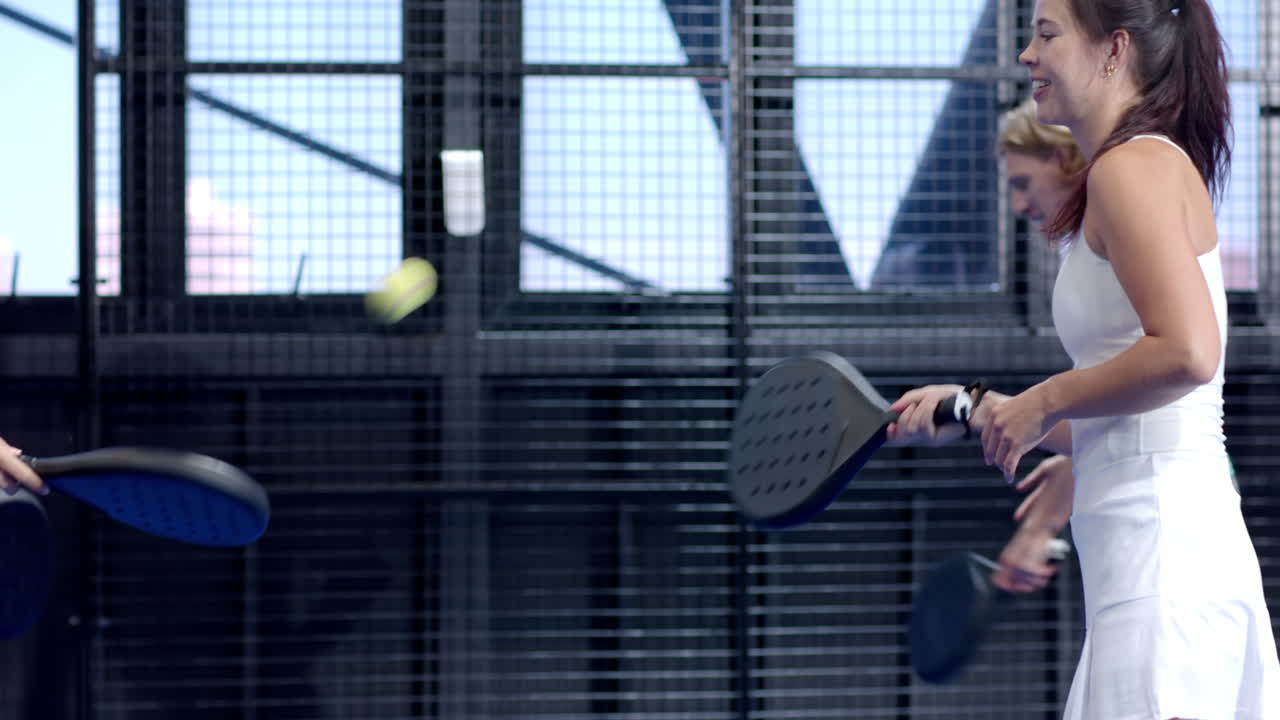 Women playing padel tennis, focusing on game, enjoying indoor sports activity, at indoor court