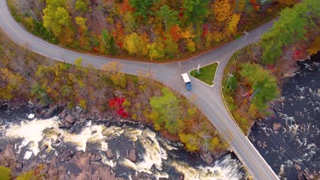 a scenic intersection surrounded by vibrant autumn foliage in mont tremblant, with a river and a bridge in the background