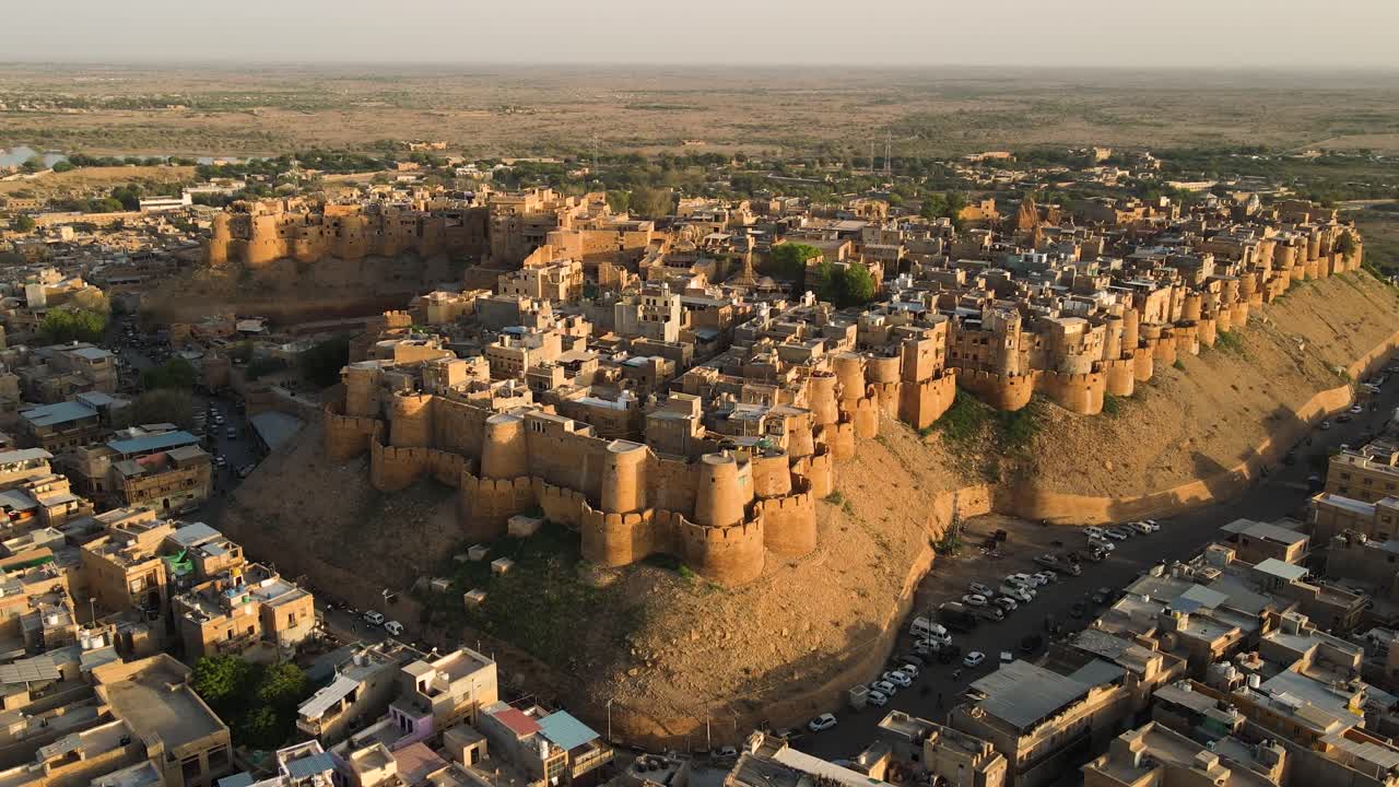 Aerial drone shot highlighting the intricate architecture of Jaisalmer Fort during a vibrant desert sunset.