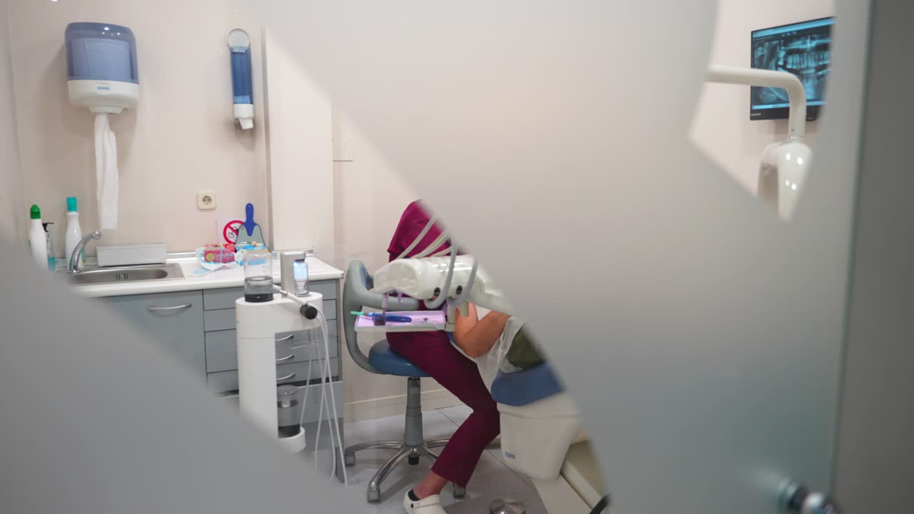 guardando attraverso una porta di vetro, un dentista che tratta un paziente