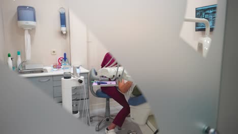 Looking-through-glass-door,-dentist-treating-a-patient