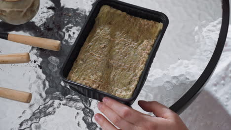 moist growing medium filling disposable tray on textured glass table next to scattered gardening tools and soil remnants during indoor planting setup under soft lighting in bright home environment