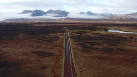 aerial reveal drone video of a road running through black desert with a majestic mountain range in the icelandic landscape: famous attractions and landmark destinations in icelandic nature