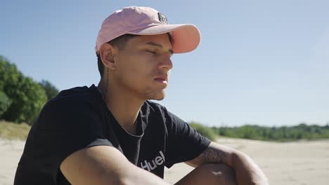 joven adulto masculino latino sentado solo en una playa desierta, disfrutando de la vista