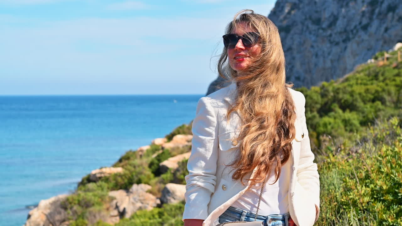 Woman by the blue sea on the rocks in Calpe, Spain
