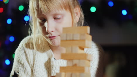 girl pulls wooden blocks from the tower - a game for training accuracy