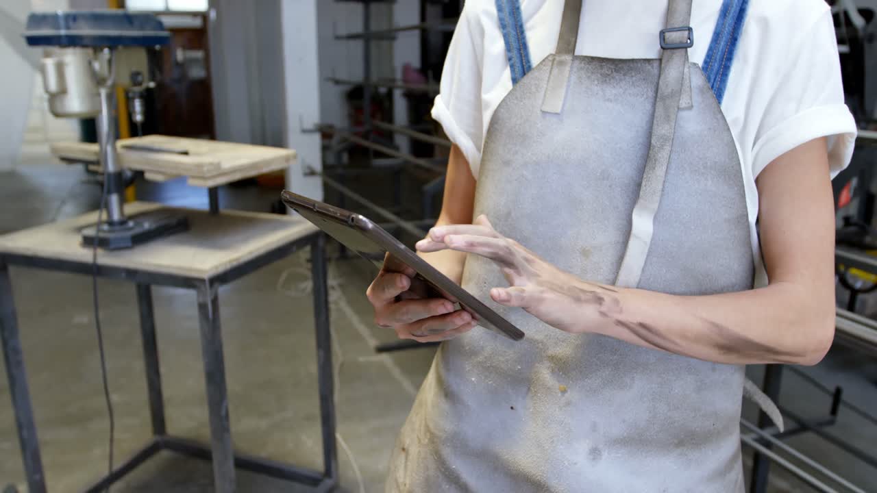 Female welder using digital tablet in workshop 4k
