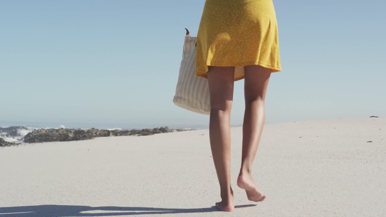 mujer afroamericana caminando por la costa