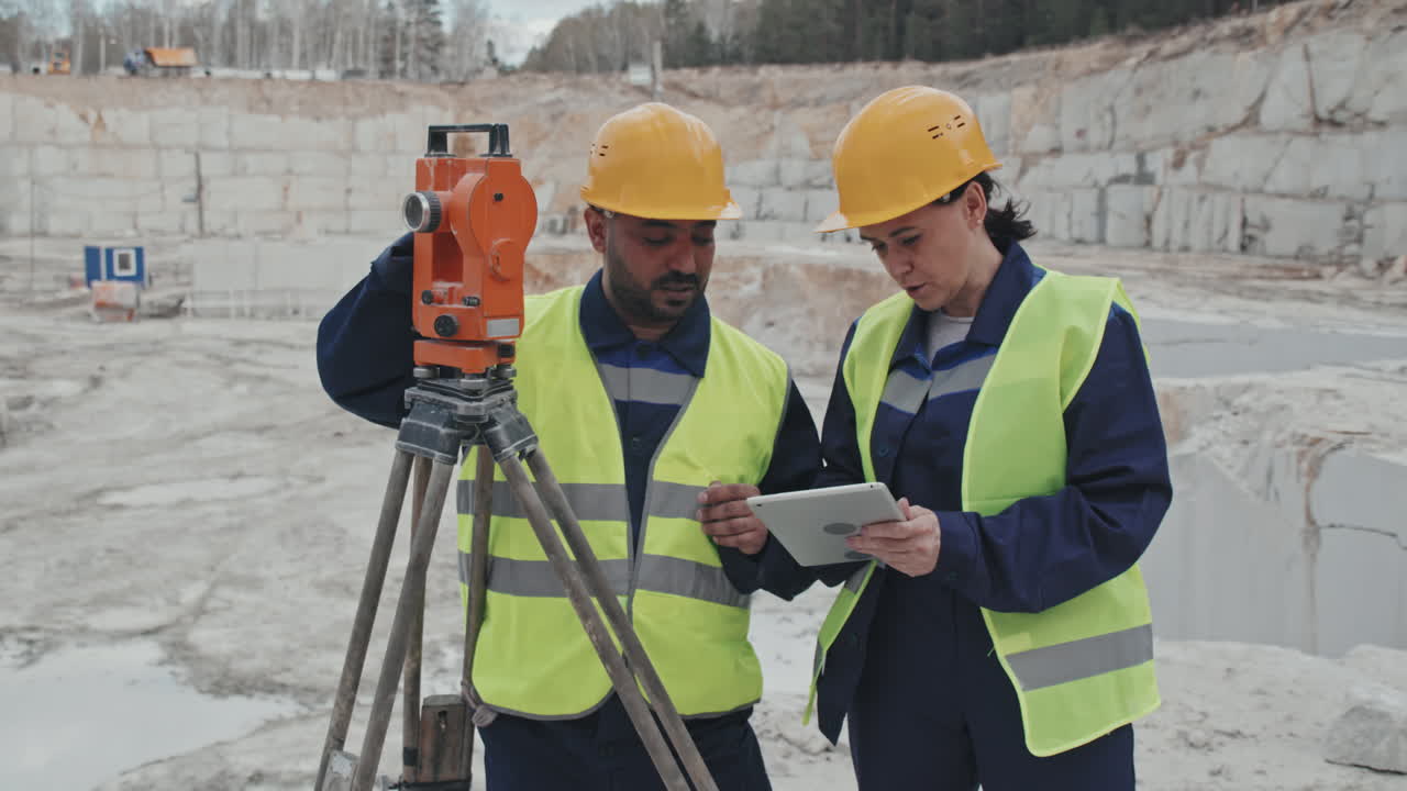 Workers Using Surveying Measuring Equipment in Quarry