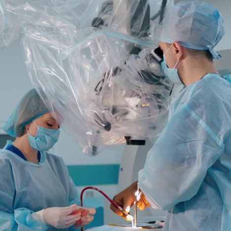 medical procedure in the operating theater. surgeon together with a nurse perform neurosurgery through electron microscope in the modern hospital.