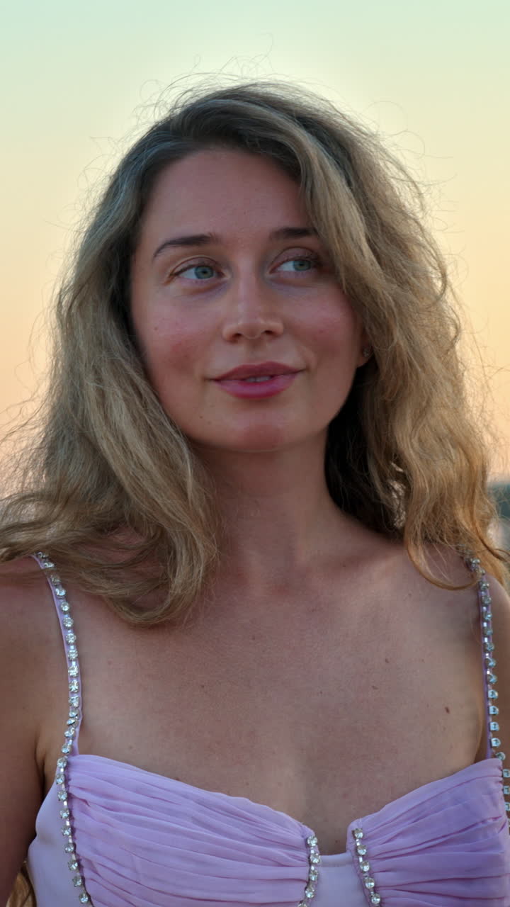 Donna con vestito rosa che posa sulla spiaggia di sera a Cannes, in Francia