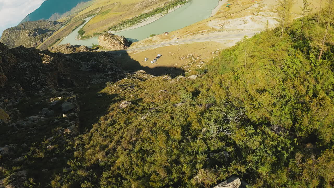 un río vibrante talla un camino cerca de la autopista. una base turística acogedora situada contra altos acantilados en el corazón de un valle bañado por el sol. un estilo de vida de campamento