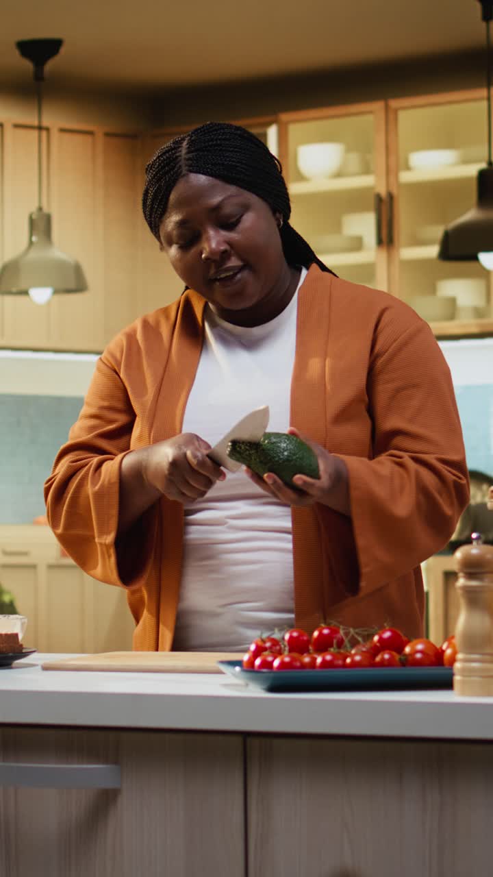 Video verticale di una food blogger che riprende un tutorial passo-passo su come tagliare un avocado in interni.