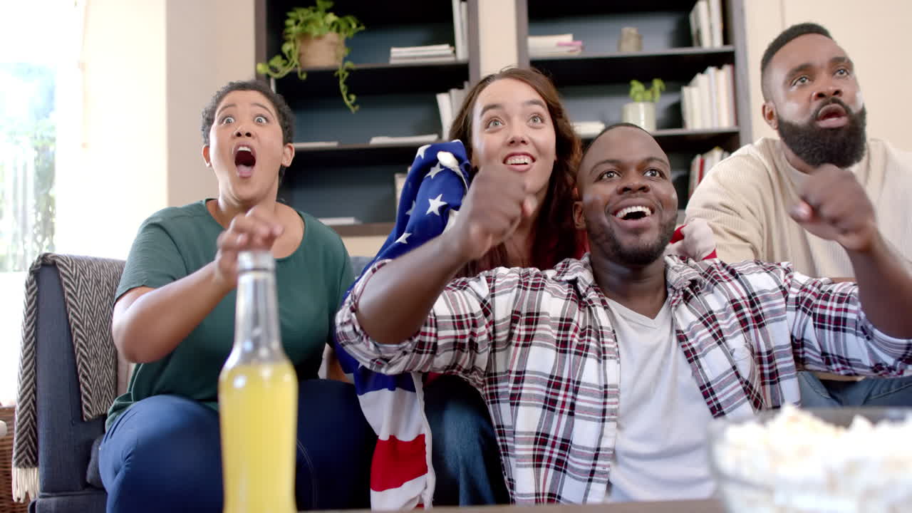 Group of friends cheering and celebrating while watching sports game at home