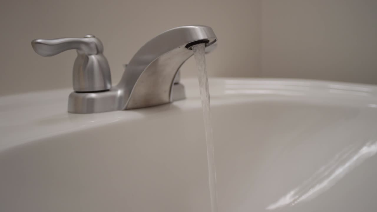 Loop of water running from a tap in bathroom sink