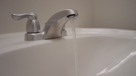 loop of water running from a tap in bathroom sink