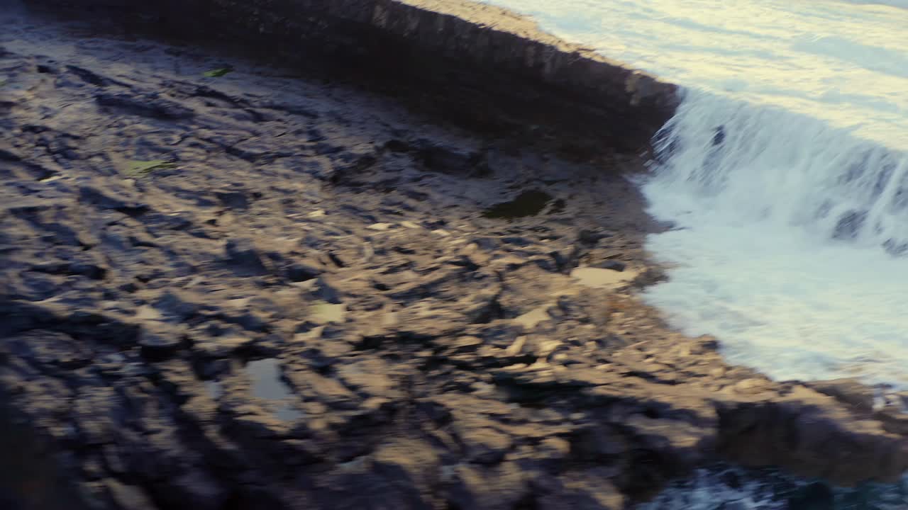 Aerial View of a Dramatic Waterfall Cascading Down a Dark Rocky Cliff