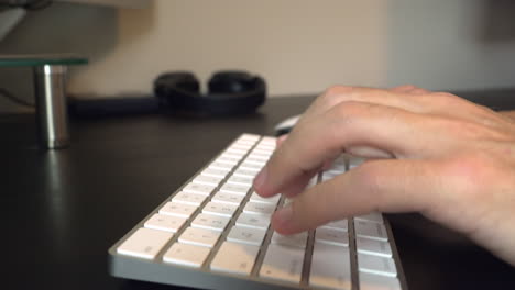 Close-up-slider-shot-of-man-typing-on-white-keyboard-and-moving-mouse