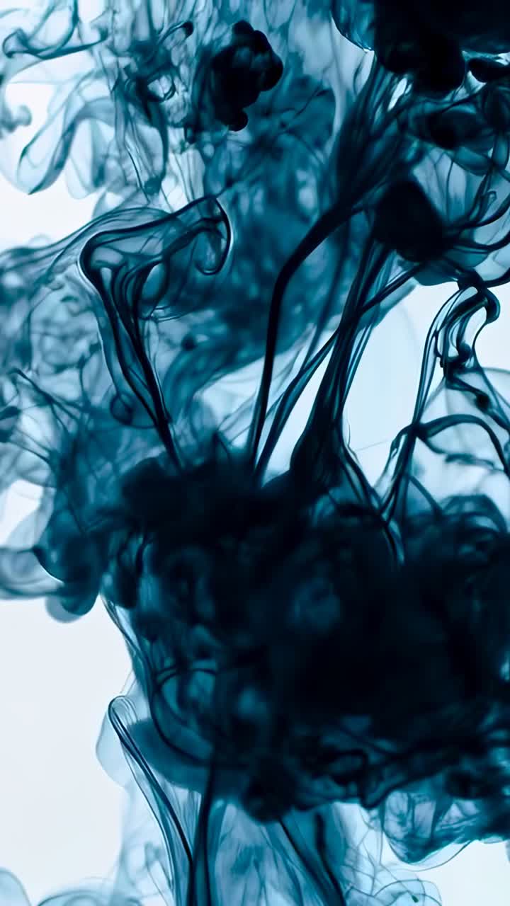 Video verticale: goccia che rilascia pennacchi blu scuro che si sollevano e si mescolano in un fluido trasparente, retroilluminato