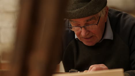 experienced senior shipwright working on wooden boat in workshop