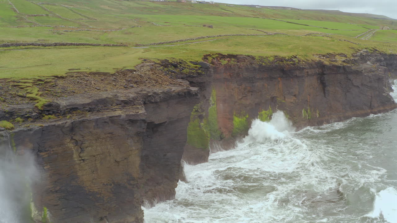 Aerial tracking shot captures the wild Atlantic Ocean beating the Cliffs of Moher in Doolin during a storm