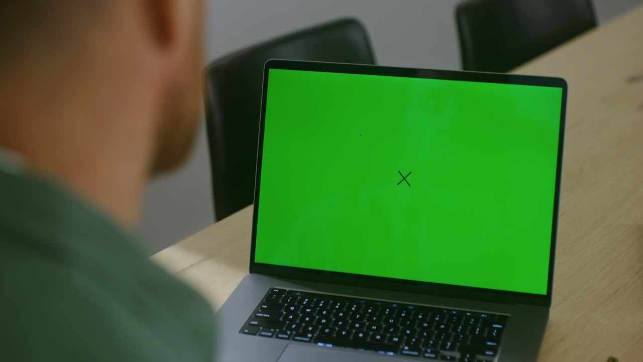 Person looking at a laptop with a green screen