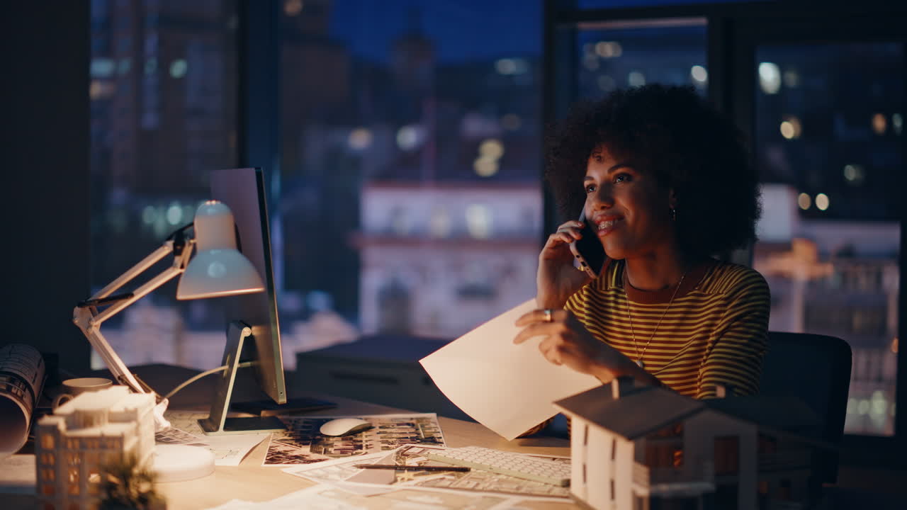 Woman realtor talking mobile phone at night office closeup. Smiling architect