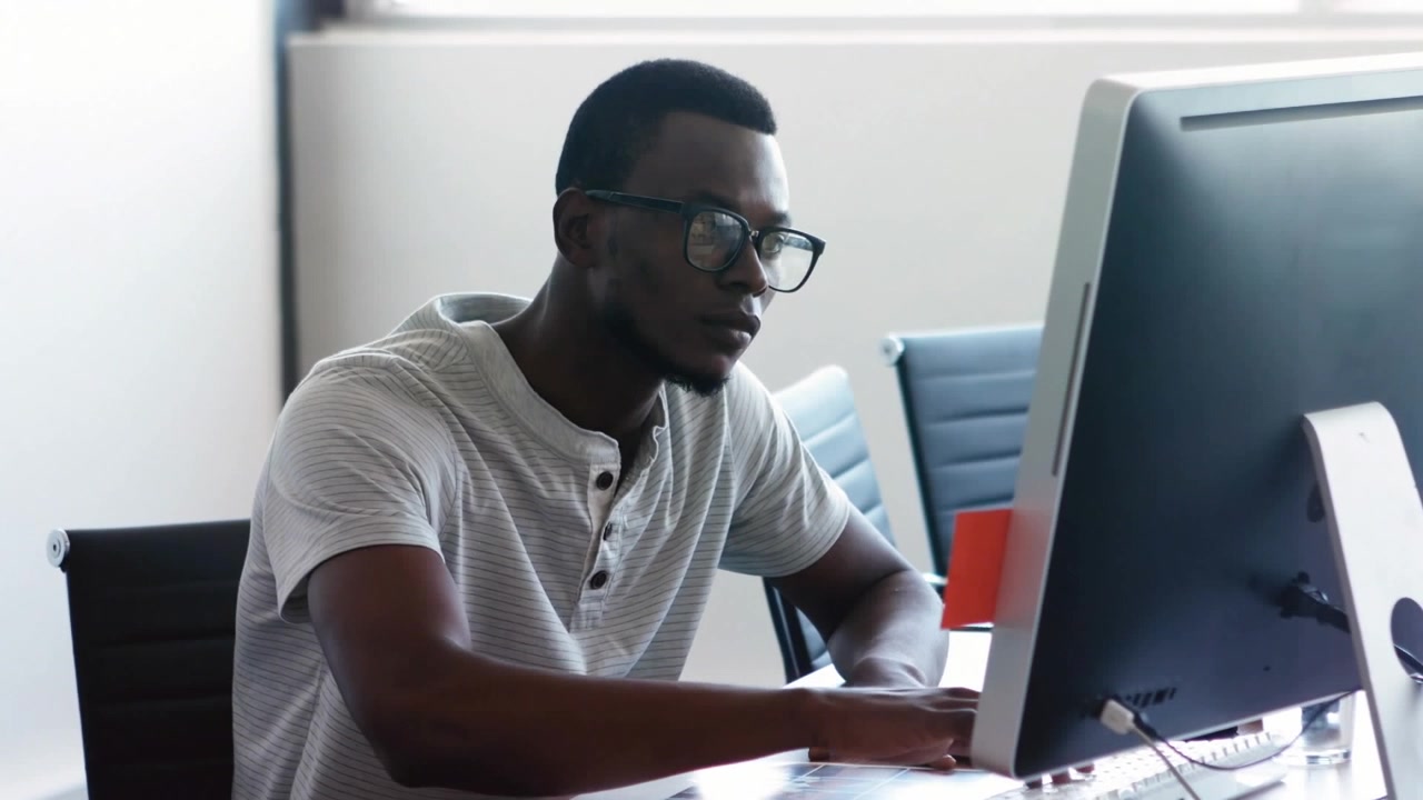 Animation des Textes 'Vibes' über einem afroamerikanischen Mann, der im Büro am Desktop arbeitet.