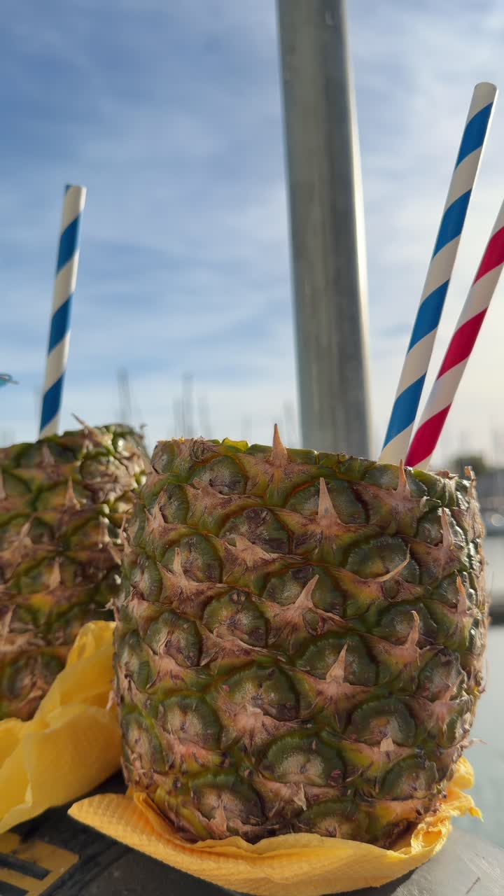 Cocktail rinfrescanti all'ananas con cannucce e ombrellino in una marina soleggiata