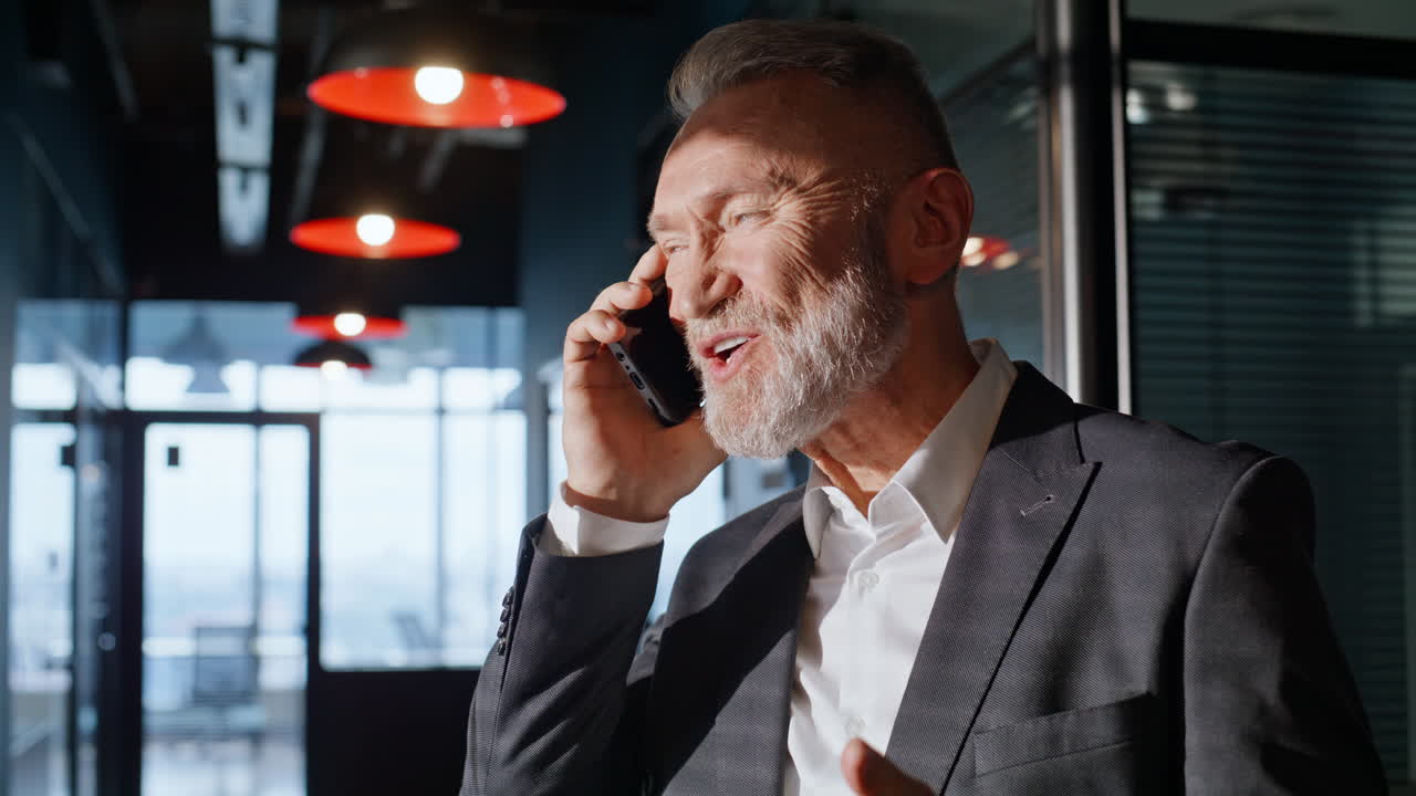 Smilende bedriftseier som ringer med mobiltelefonen og nyter samtalen i en hall, nærbilde