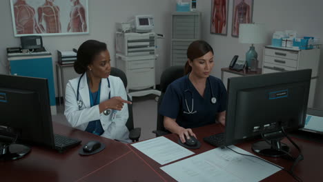 two female medical professionals working at computers in an office