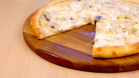 pizza without one slice with mushrooms mushrooms and cheese on wooden board on the table. close-up side view.