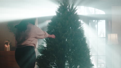 woman prepares christmas tree in bright sunlight