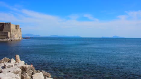 rocky shore with ovo castle on the gulf of naples in italy