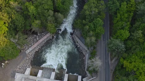 descending drone shot of a dam on a canadian river in ontario in summer with lots of whitewater flowing
