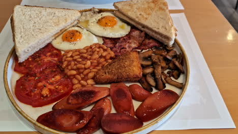 traditional english breakfast - plate with fried eggs, sausages, beans, mushrooms and bacon