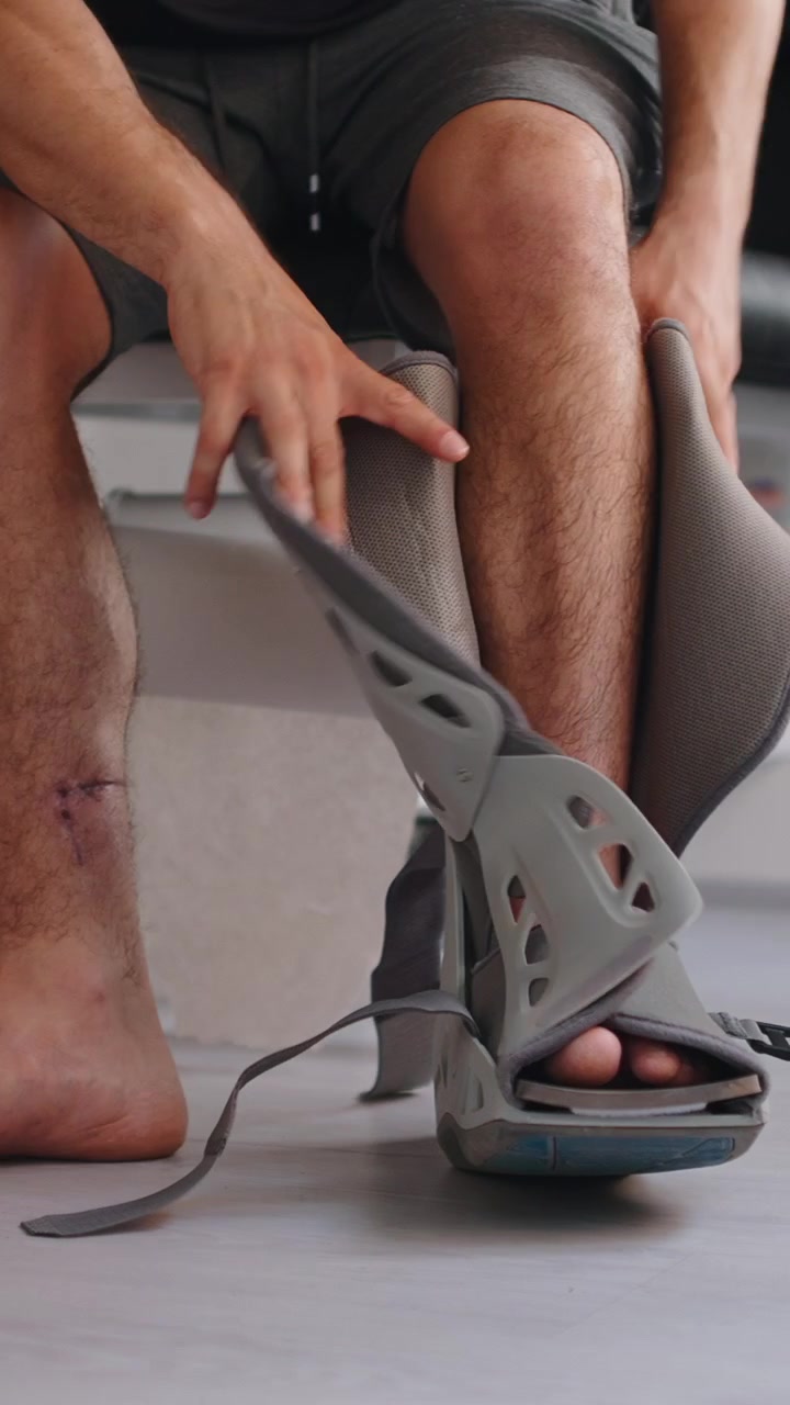 Homme retirant une botte de marche orthopédique de sa jambe blessée