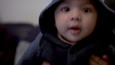 adorable 4 month old baby wearing navy hooded cardigan with bear ears moving whilst being held