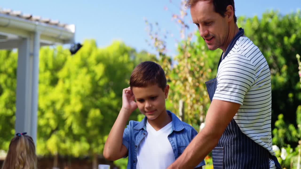 padre e hijo asando salchichas y maíz en la barbacoa