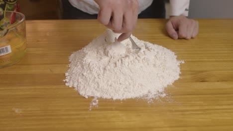 spreading and evening out the dough on wooden kitchen table with the fork