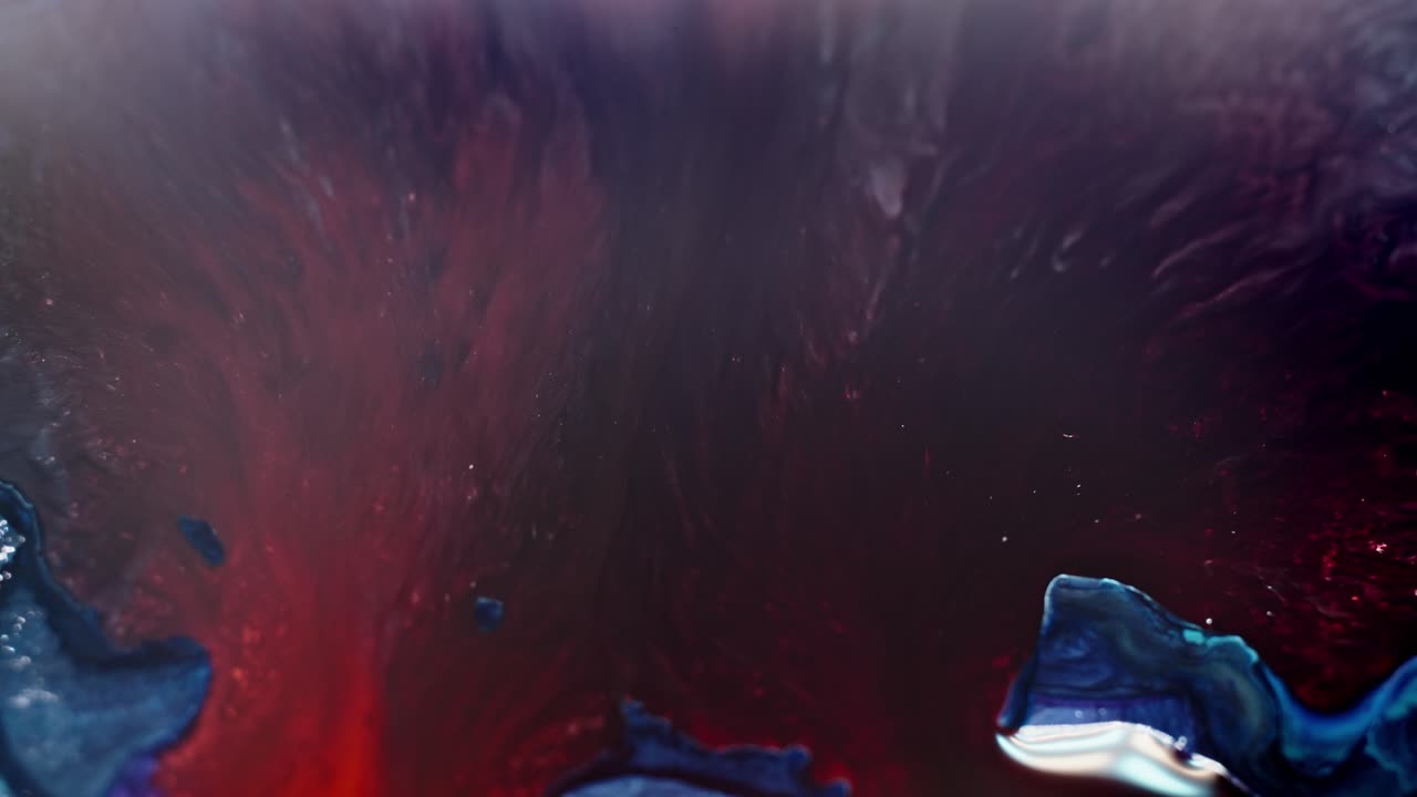 vista aérea abstracta de tinta roja y azul difundida en el agua, parecida a una nebulosa cósmica