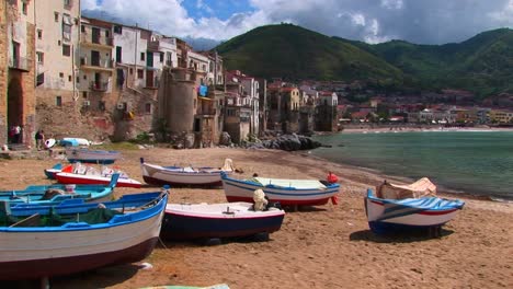 boats on a beach next to the ocean and houses in cefalu italy